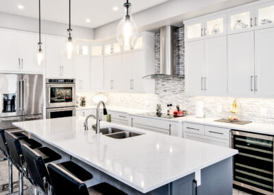 Designer kitchen with bright cabinets and countertops as well as some dark accents and silver appliances.