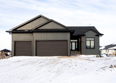 Exterior shot of a custom-built home in south eastern Manitoba. Dark exterior with wood accents.