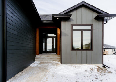 The exterior of a custom-built home in southeastern Manitoba. Dark exterior with wood accents and paneling.