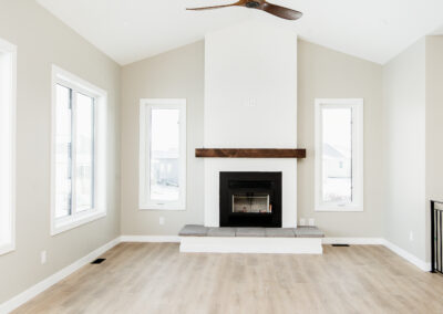 Bright living room with a fireplace and great fan accent. Vaulted Ceilings. Custom-built home.