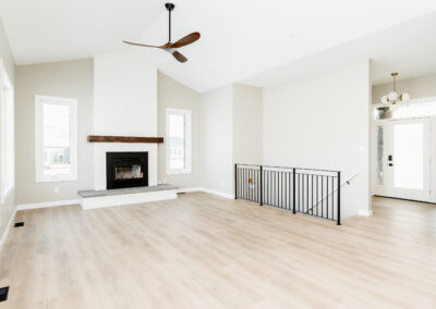 Bright living room with a fireplace and great fan accent. Vaulted Ceilings. Custom-built home.